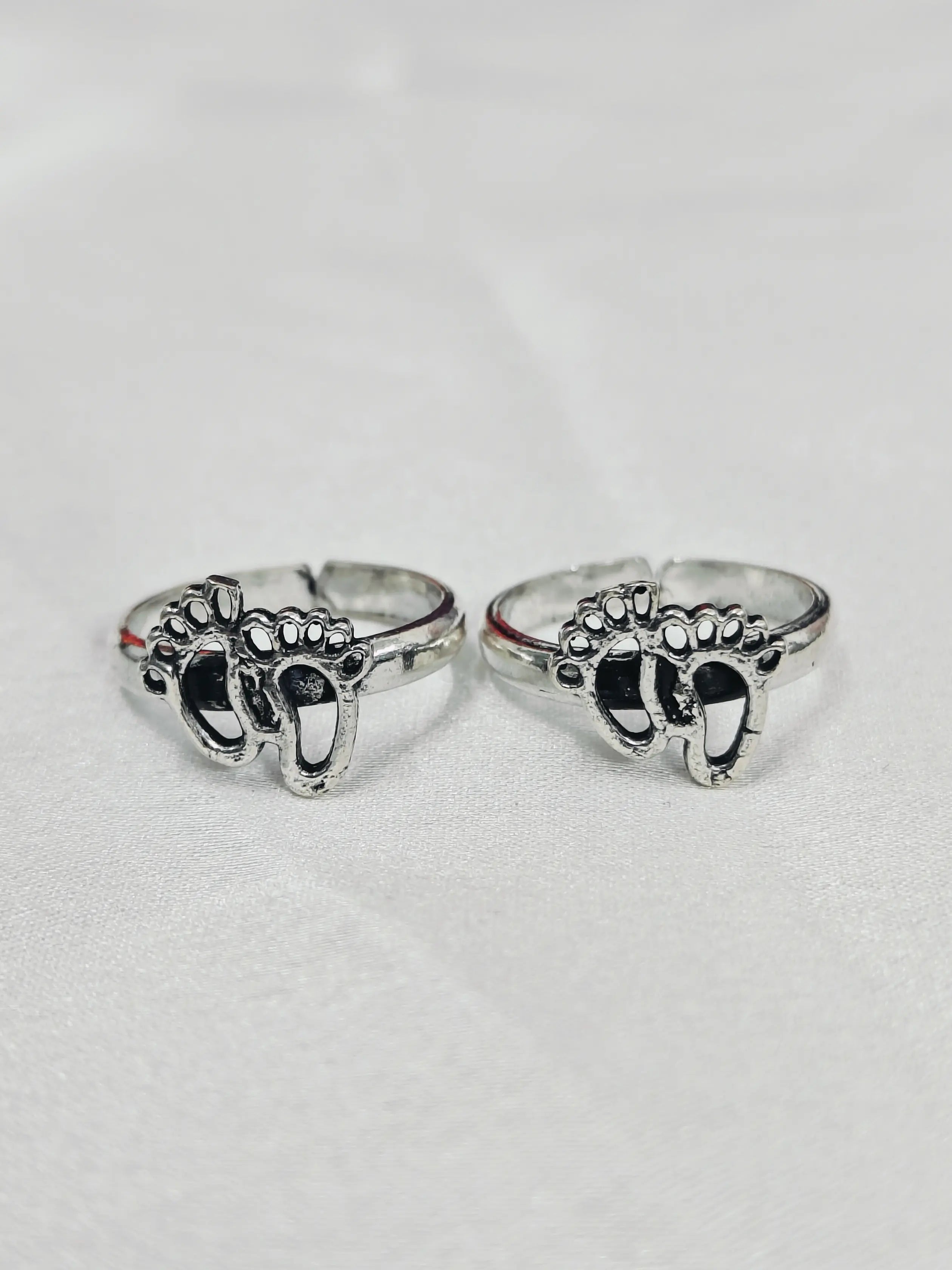 Two silver rings with elephant designs on a light gray background